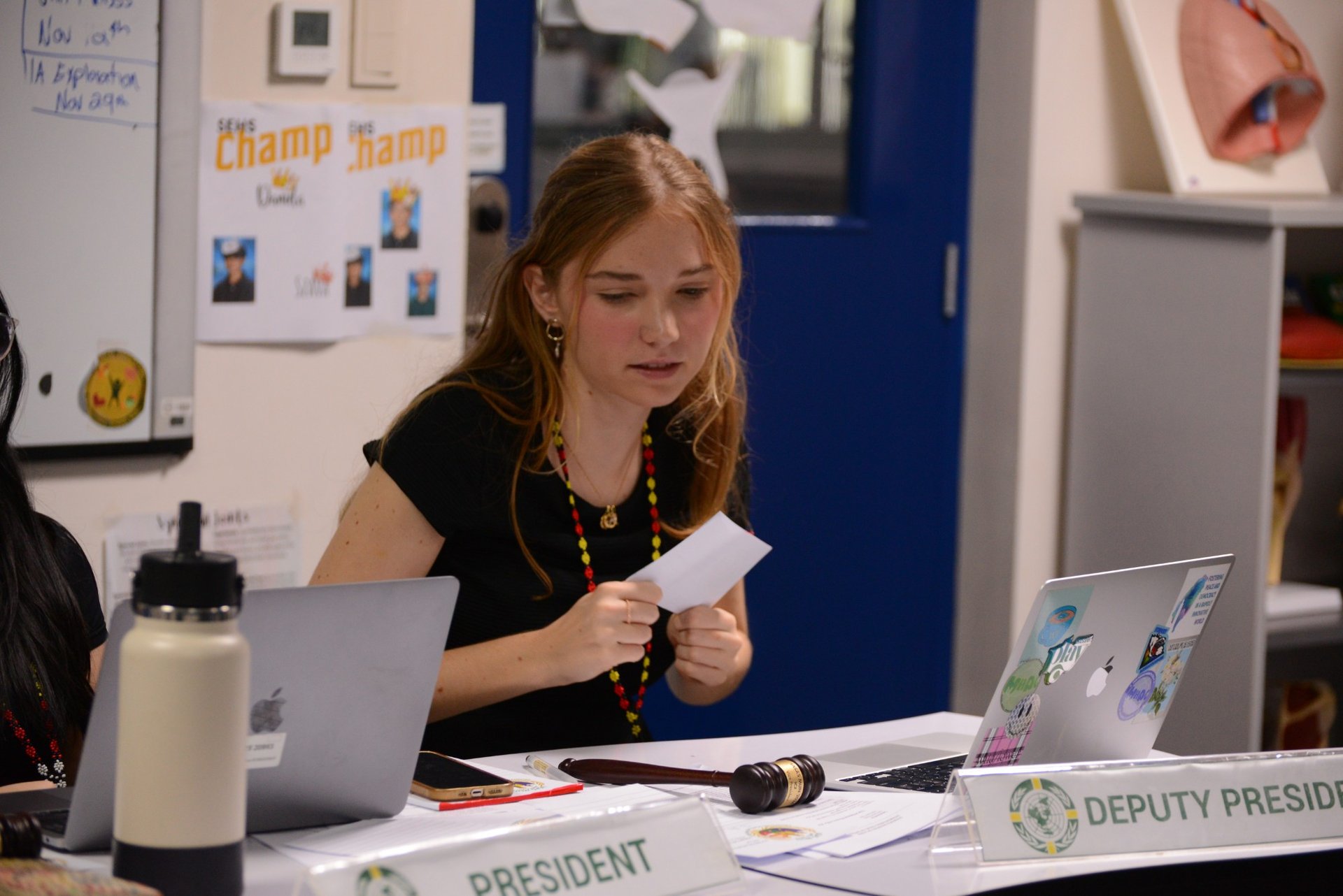 A committee President reading a note at the dais